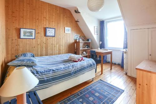 ein Schlafzimmer mit einem Bett in einem Zimmer mit Holzwänden in der Unterkunft CABESTAN - Maison de famille au coeur du bourg - Vue Mer in Carantec
