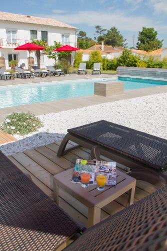 a table with drinks on it next to a pool at Hôtel Le Vert Bois in Dolus d'Oléron