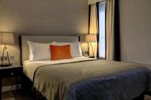 a bedroom with a bed with an orange pillow on it at Ten Hill Place in Edinburgh