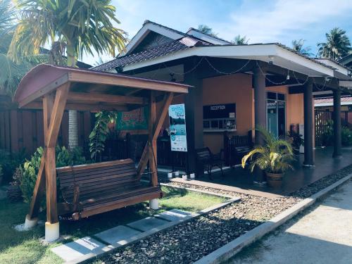 a wooden bench in front of a house at Chuu Pun Village Resort in Pantai Cenang