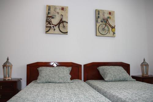 um quarto com duas camas e duas fotos de uma bicicleta na parede em House of Orchids with Pátio em Vila Real de Santo António