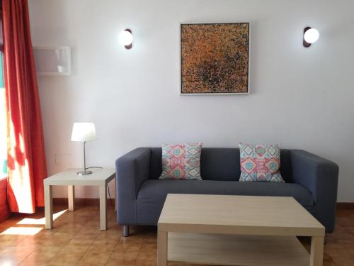 a living room with a blue couch and a table at Apartamentos Las Palmeras I in Puerto del Carmen