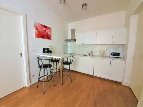 a kitchen with white cabinets and a table and stools at Apartment Sophia in Prague