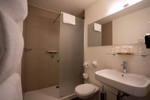 a bathroom with a sink and a toilet and a shower at Gosset Hotel in Groot-Bijgaarden