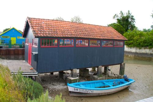 a blue house with a boat in front of it at Hôtel Le Vert Bois in Dolus d'Oléron