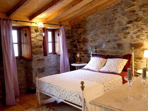 - une chambre avec un lit et un mur en pierre dans l'établissement Casa Aigra, à Góis