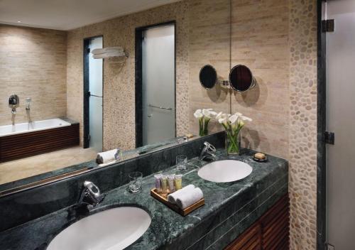 a bathroom with two sinks and a mirror at Mövenpick Resort & Spa Dead Sea in Sowayma