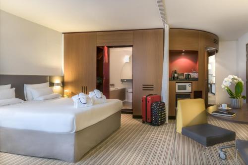 カンヌにあるノボテル スイート カンヌ センターの大きなベッドとデスクが備わるホテルルームです。