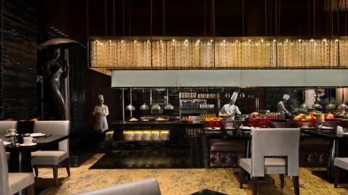 a restaurant with a bar with chefs preparing food at InterContinental Shanghai Jing' An by IHG in Shanghai