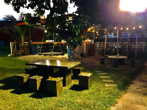 a picnic table and bench under a tree at night at Winter House Chiang Rai in Chiang Rai