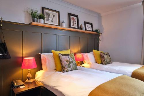 two beds in a room with two lamps and a phone at The Bulls Head Hotel in Bromley