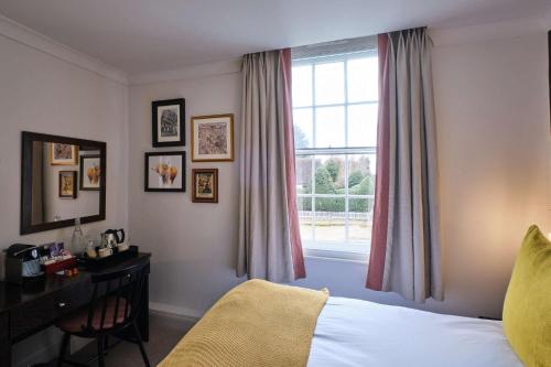a bedroom with a bed and a desk and a window at The Bulls Head Hotel in Bromley