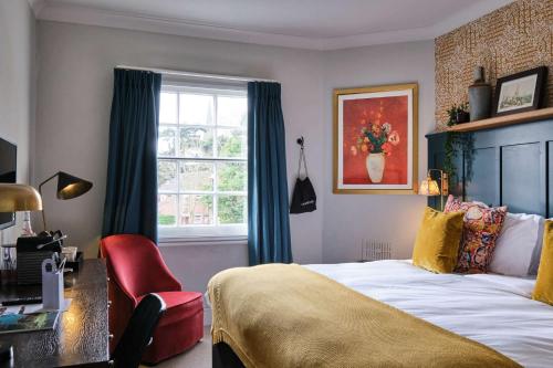a bedroom with a bed and a desk and a window at The Bulls Head Hotel in Bromley