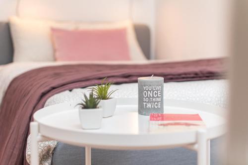 a white table with two plants on it next to a bed at Palm Aparts Warsaw in Warsaw