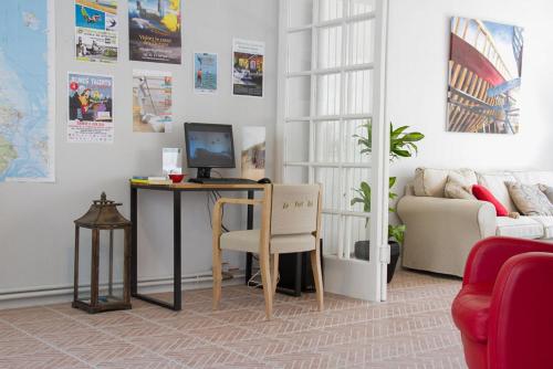 a living room with a table with a computer on it at Hôtel Le Vert Bois in Dolus d'Oléron