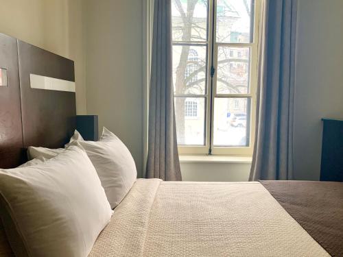 a bedroom with a bed with white pillows and a window at Hôtel Sainte-Anne in Quebec City