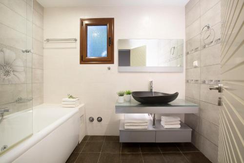 a bathroom with a sink and a tub and a mirror at Arodo Seaside Villas - Villa Christina in Sivota