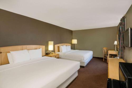 a hotel room with two beds and a television at Travelodge by Wyndham Memphis Airport/Graceland in Memphis
