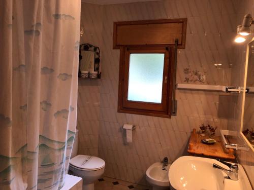 uma casa de banho com um lavatório, um WC e uma janela. em APARTAMENT NORAY 2B BARRUERA 6P em Barruera