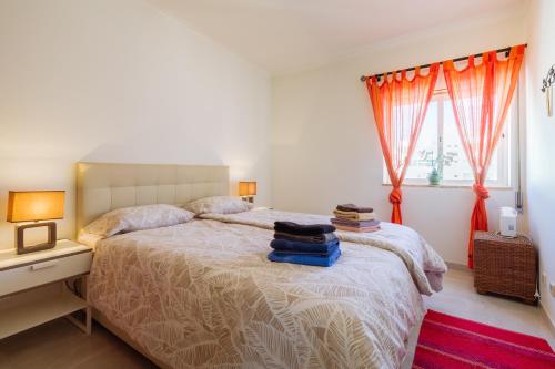アルマカオ・デ・ペラにあるApartment Dean direkt am Meerのベッドルーム1室(オレンジ色のカーテンが付いた大型ベッド1台付)