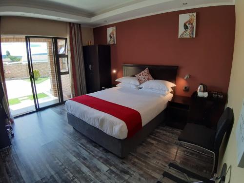 um quarto com uma cama grande e uma parede vermelha em Citystay Ladybrand em Ladybrand