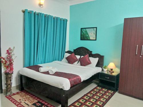 a bedroom with a large bed with blue walls at Coorg Homeland Homestay -With Kitchenette in Madikeri