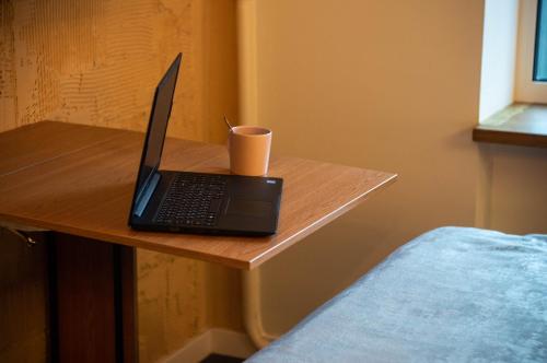 a laptop computer sitting on a wooden table with a cup at Kyiv Panorama Apartments near Gulliver in Kyiv