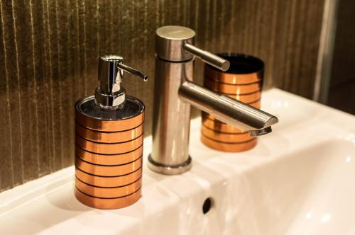 a bathroom sink with a faucet and two soap dispensers at Kyiv Panorama Apartments near Gulliver in Kyiv