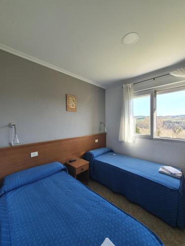a bedroom with two beds and a window at Pensión Portomiño in Portomarin