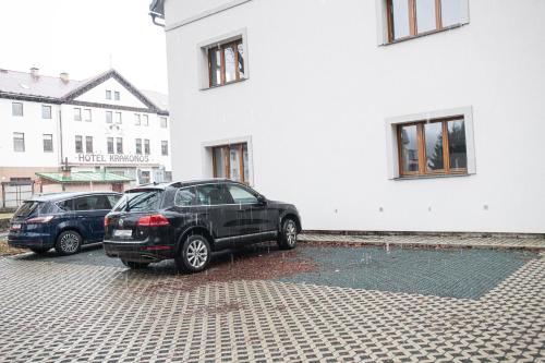 dos autos estacionados en un estacionamiento al lado de un edificio en Rocky Apartment en Rokytnice nad Jizerou
