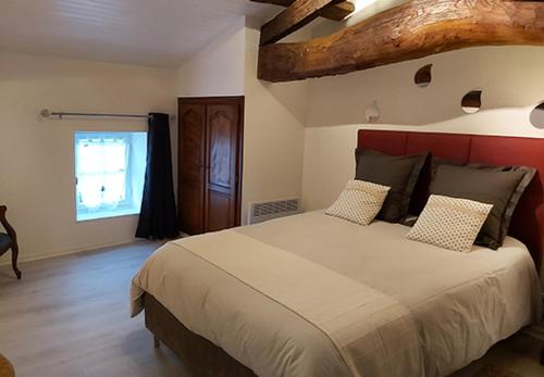 a bedroom with a large bed with a red headboard at Logis Des Bessons in Migron
