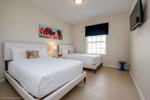a bedroom with two beds and a flat screen tv at Cozy Condo wPrivate Balcony & FREE Resort Access in Orlando