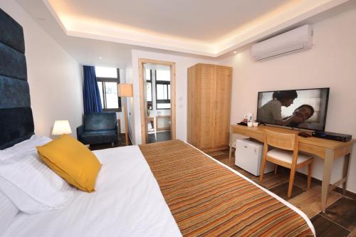 a bedroom with a bed and a desk and a television at Tzukim Boutique - Desert Traveler's Hotel in Mitzpe Ramon - מלון בוטיק צוקים in Mitzpe Ramon