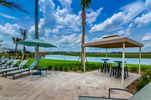 a patio with chairs tables and umbrellas next to a lake at 4814 Lullaby Lane in Kissimmee