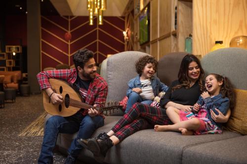 a family sitting on a couch playing a guitar at Ibis Abdelmoumen Casa Centre in Casablanca