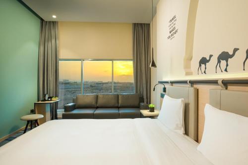 a hotel room with a bed and a couch at Swiss-Belinn Airport Muscat Oman in Muscat