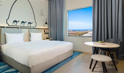 a hotel room with a bed and a table and a window at Swiss-Belinn Airport Muscat Oman in Muscat