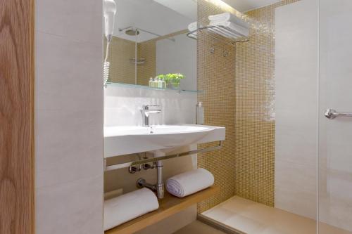 a white bathroom with a sink and a shower at Hotel Dei Pini in Alghero