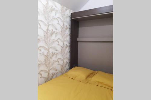- une chambre avec un lit jaune et un mur dans l'établissement L'Essentiel, studio cosy, quartier Anatole France, CHU, à Rennes