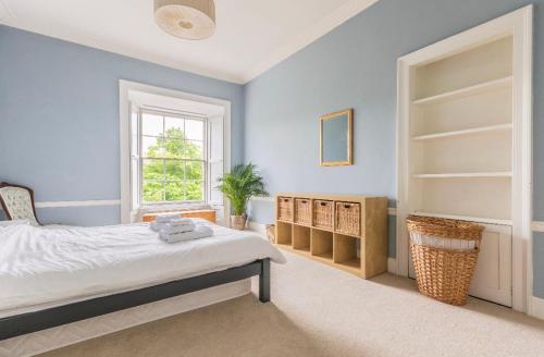 a bedroom with blue walls and a bed and a window at New Town Apartment with Castle View in Edinburgh
