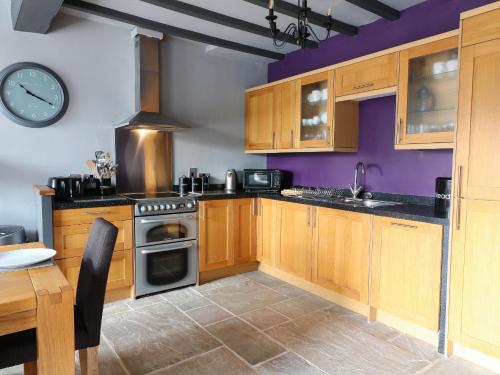 a kitchen with wooden cabinets and a clock on the wall at Royal Oak in Matlock