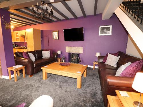 a living room with purple walls and leather furniture at Royal Oak in Matlock