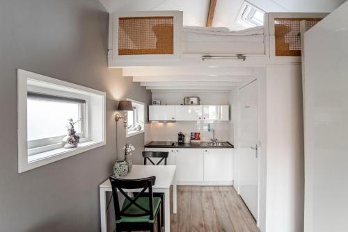 a kitchen with white cabinets and a table and chairs at Beach House Zandvoort in Zandvoort