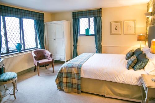 a bedroom with a bed and a chair and windows at The Red Lion Hawkshaw in Bury