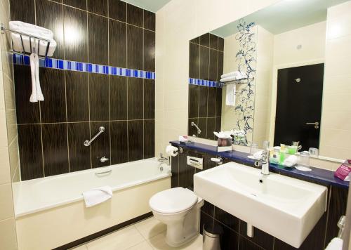 uma casa de banho com um lavatório, um WC e uma banheira em Crowne Plaza Dublin Blanchardstown, an IHG Hotel em Blanchardstown