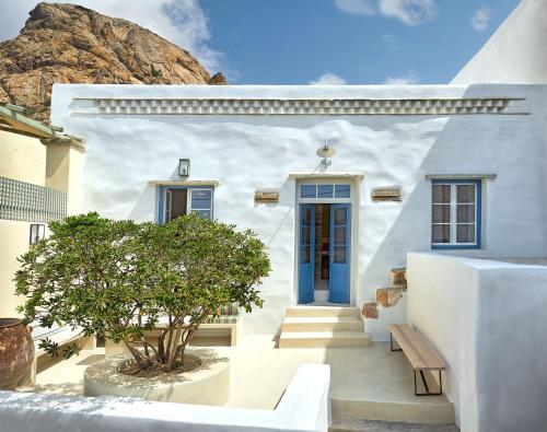 a white house with a blue door and a tree at Xinara House Old Blacksmiths in Tripótamos
