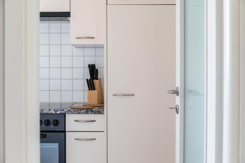 a kitchen with white cabinets and a stove at Lido Apartments by Quokka 360 - 5 min from the centre and the Lugano Lido in Lugano