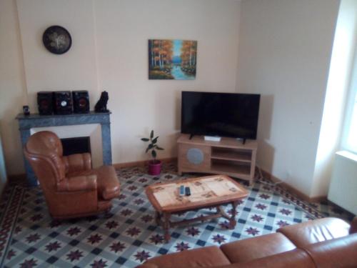 a living room with a couch and a table and a television at L'octodon in Le Grand-Pressigny