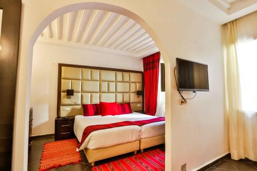 1 dormitorio con 1 cama grande con almohadas rojas en Hôtel Mechouar Plaza, en Essaouira