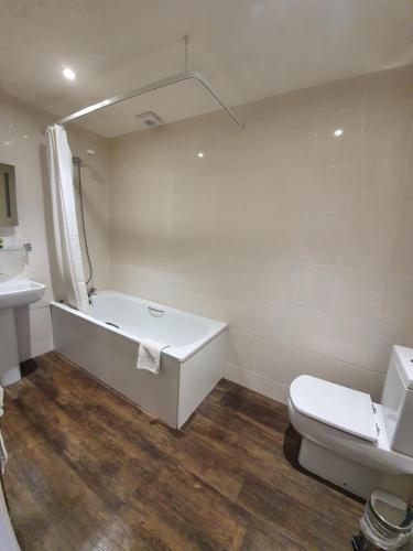 a bathroom with a tub and a toilet and a sink at Brooklands Lodge in Bournemouth